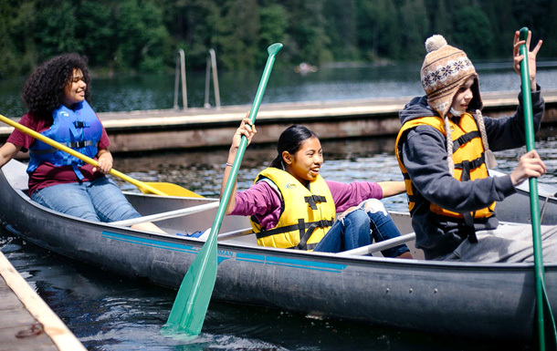 Three Girl Scouts in life jackets canoeing on the lake